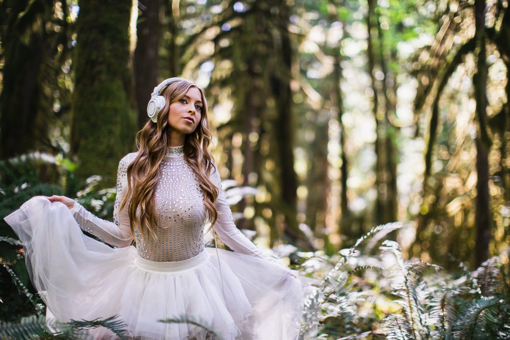 Leanne in white headphones twirling her tulle skirt in a sunlit forest