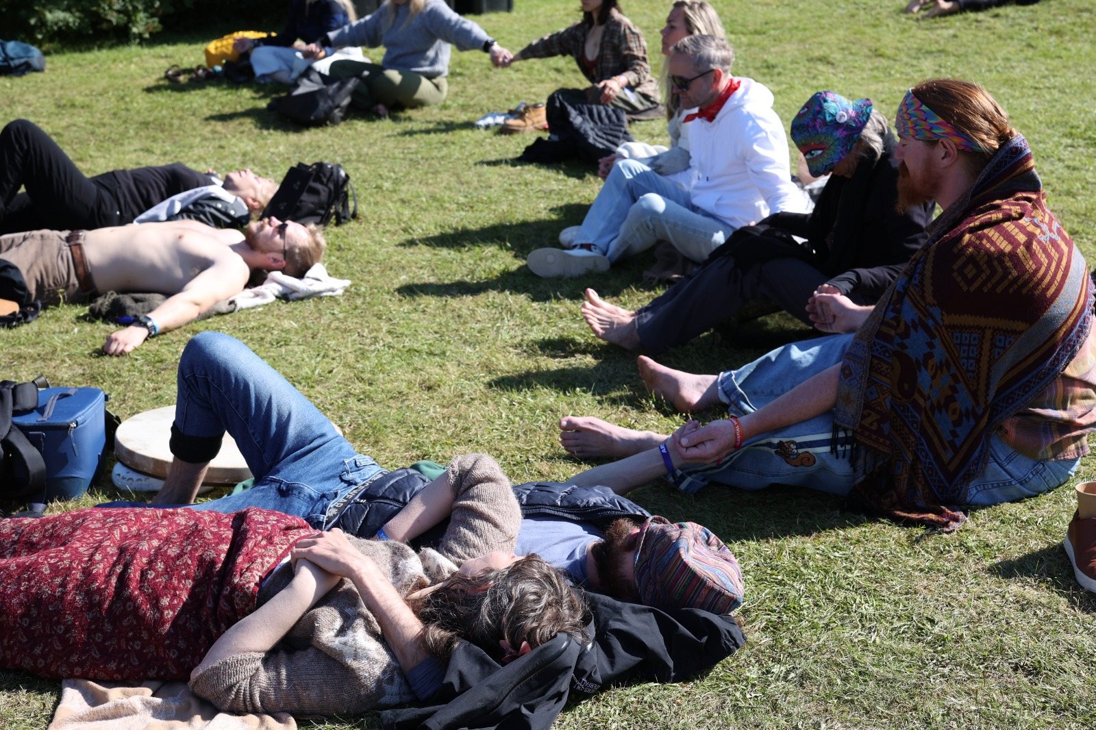 Festival-goers resting, holding hands and listening on the grass
