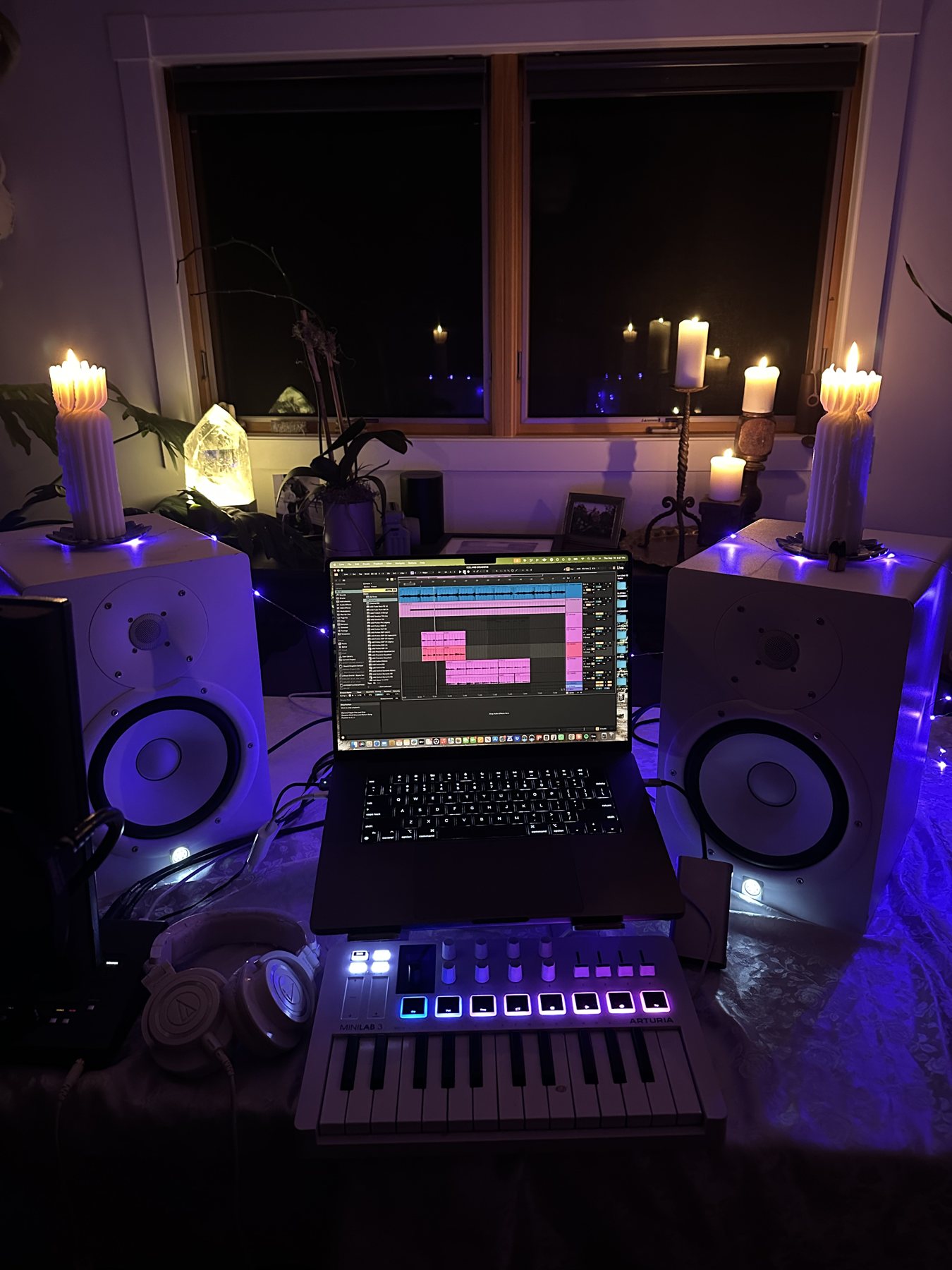 Leanne's candlelit studio: two white speakers topped with candles, a laptop running a recording session and a glowing keyboard